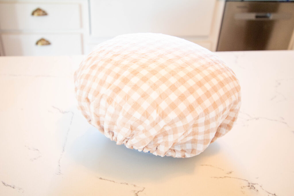 bowl of risen bread dough with checkered bowl cover over it