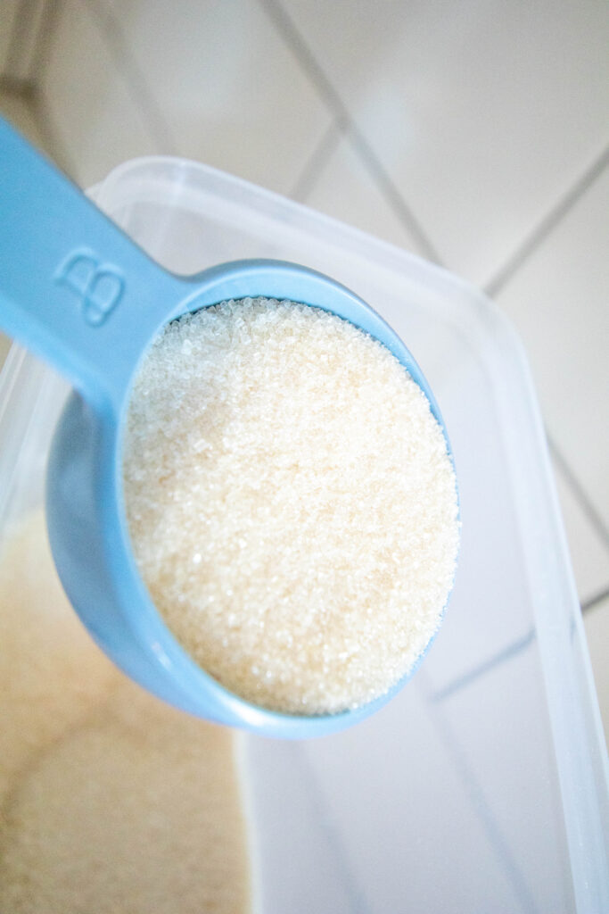blue measuring cup with cane sugar in it