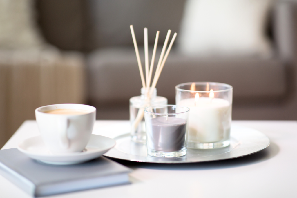 reed diffusers and candles on table next to white coffee cup