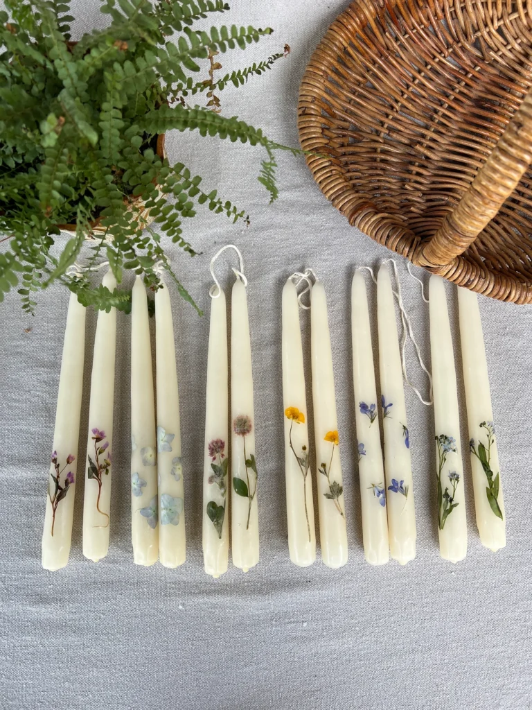 White taper candles with pressed flowers and leaves glued to them