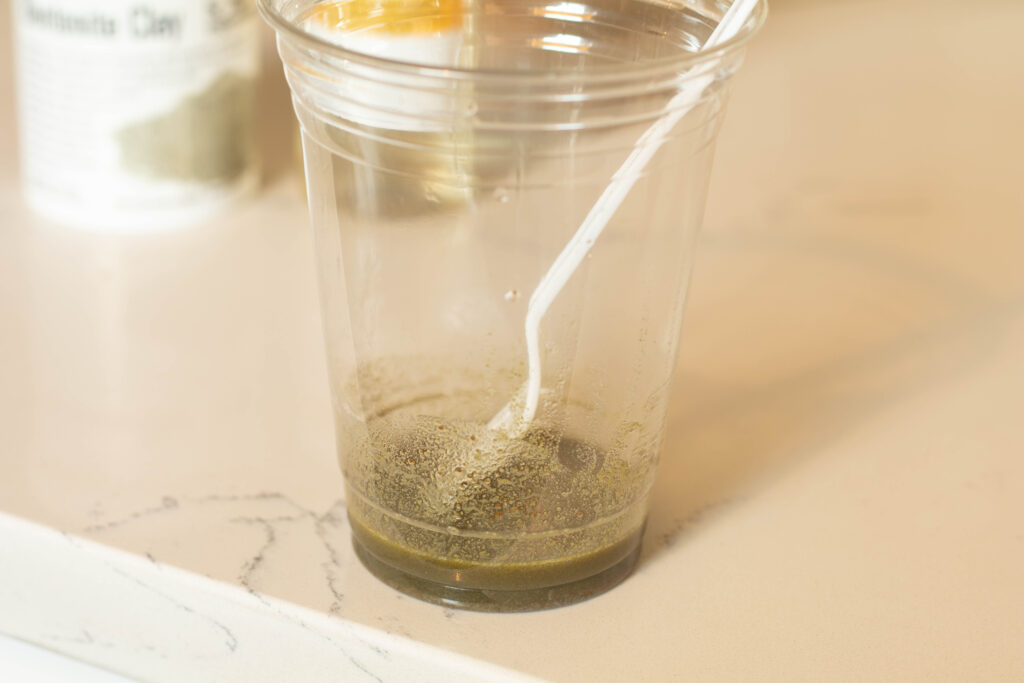 Clear plastic cup with white disposable fork with a little bit of green substance in the bottom of the cup. 