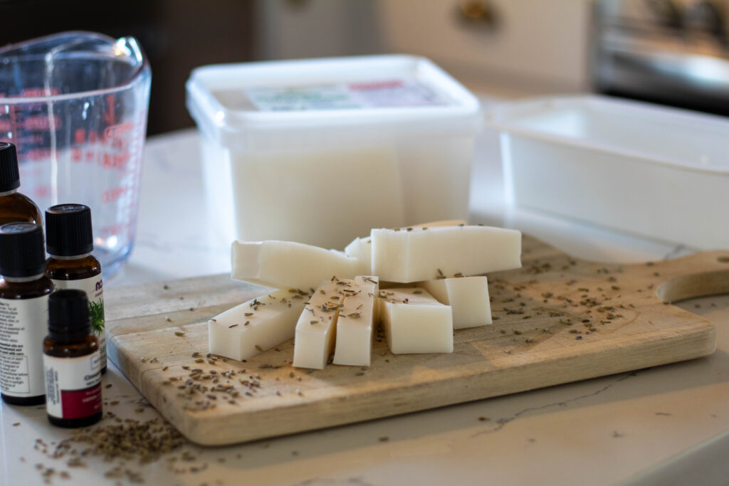 Lye-free Melt and pour soap on a cutting board surrounded by other soap making essentials. 