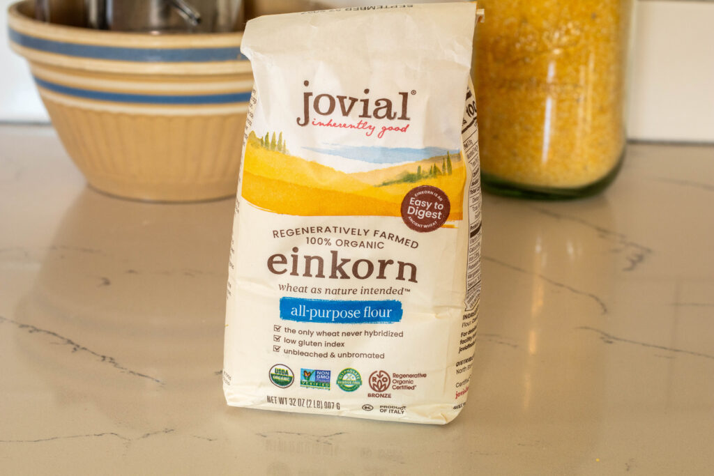 Package of Jovial all purpose einkorn flour with stone bowl and einkorn cornbread ingredients in the background. 